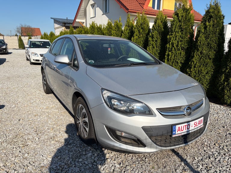 Silver Opel Astra compact car parked on gravel lot with residential houses in background