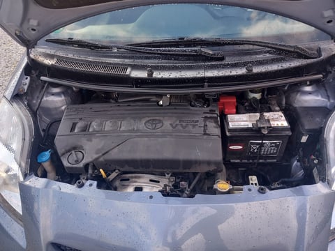 Open car engine compartment showing motor, battery, and mechanical components under the hood