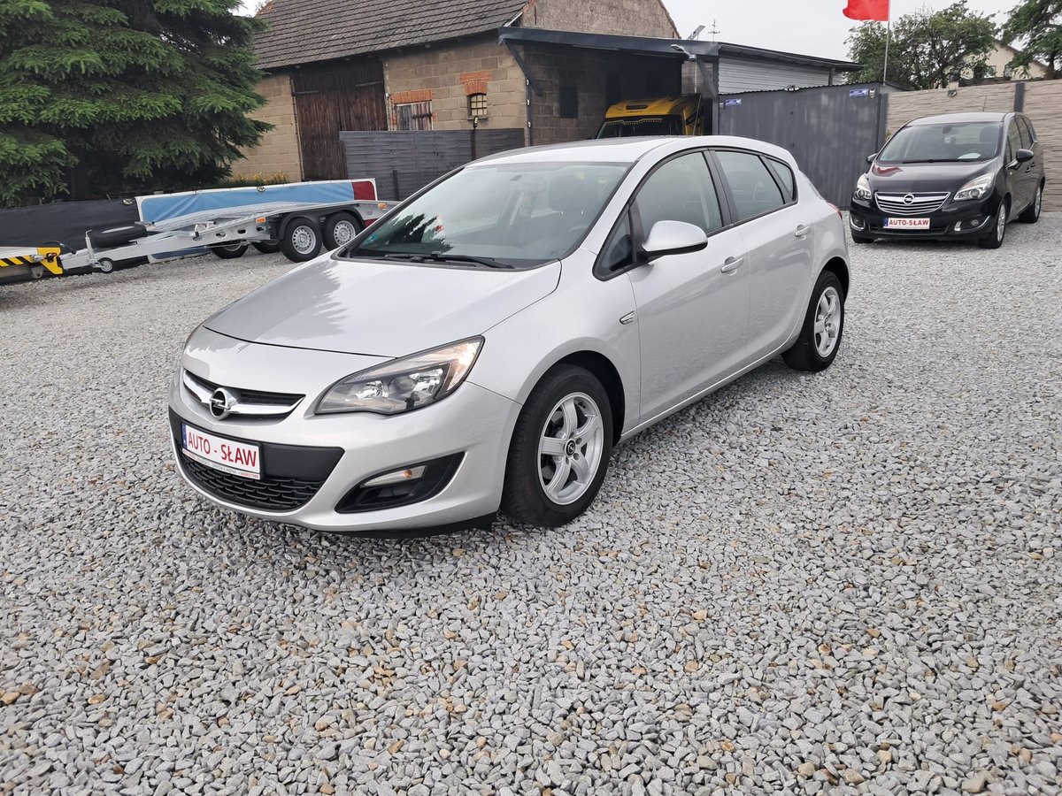Silver Opel Astra hatchback parked on gravel driveway with barn and other vehicles in background