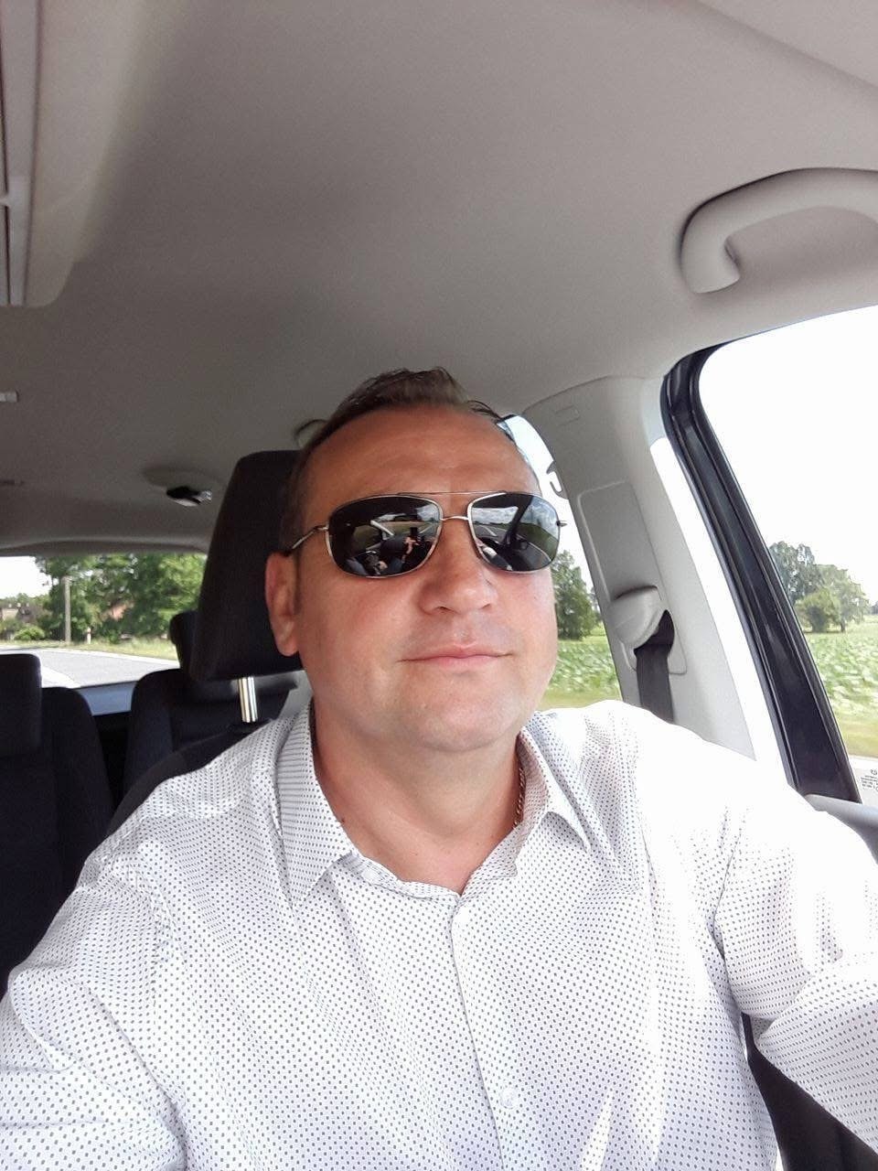 Właściciel Auto-Sław siedzący w aucie, w tle widok na pola