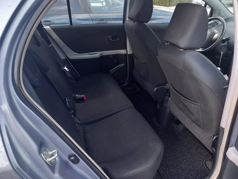 Car interior showing open rear door with black seats and carpeted floor