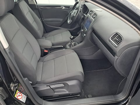 Interior of a compact car showing gray upholstered front seats, steering wheel, dashboard with air vents, and side door open