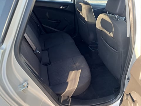 Interior view of cars back seat with black and tan upholstery, open door on left side