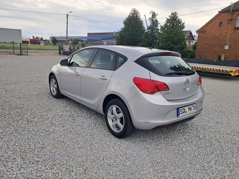White compact car parked on gravel lot with industrial buildings in background