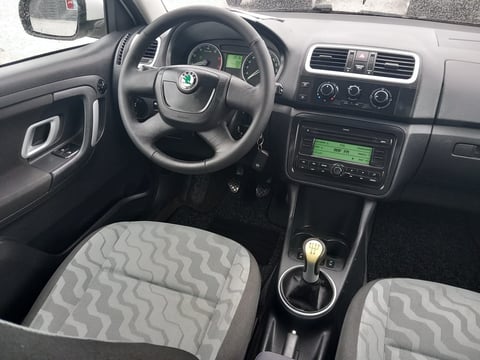 Interior view of a Skoda car showing steering wheel, dashboard, manual transmission, and patterned upholstered seats