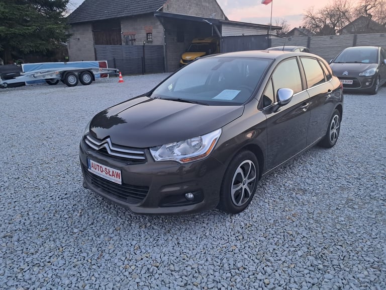 Black Citroen C1 compact car parked on gravel driveway with buildings in background