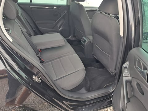 Interior view of car back seat with gray upholstered seating, open door, and side window visible