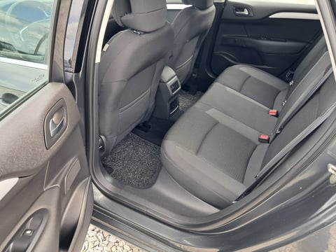 Open car door showing gray cloth interior with back seat and dark floor mat visible
