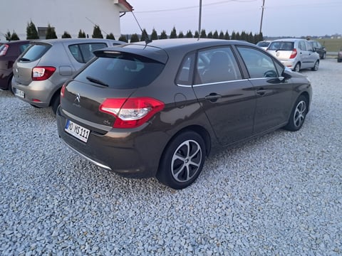 Black Peugeot hatchback car parked in outdoor lot with other vehicles and trees in background