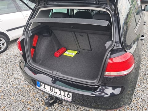 Open trunk of a black hatchback car with red emergency triangles and a yellow first aid kit inside