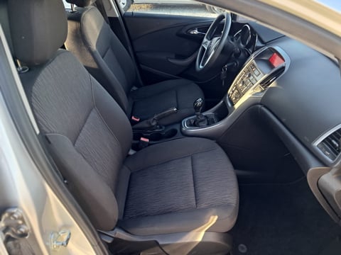 Interior view of a car showing dark fabric seats, steering wheel, dashboard with infotainment system, and gear shift