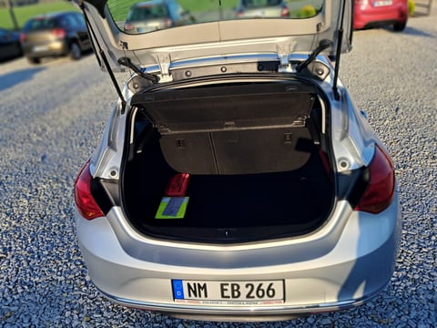 White car with open trunk displaying empty cargo space and license plate NM EB 266
