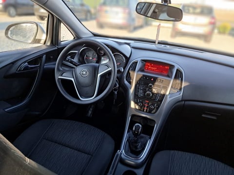 Car interior showing steering wheel, dashboard with touchscreen display, and dark blue upholstered seats viewed from passenger side